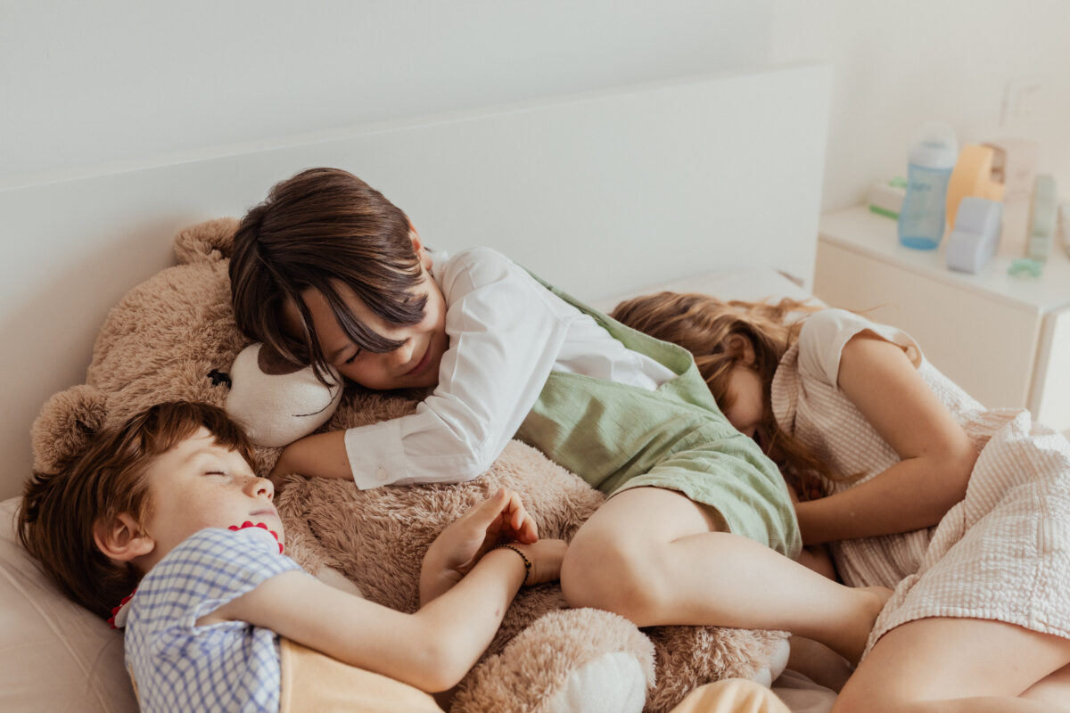 bambini dormono sul lettone abbracciati a un peluche