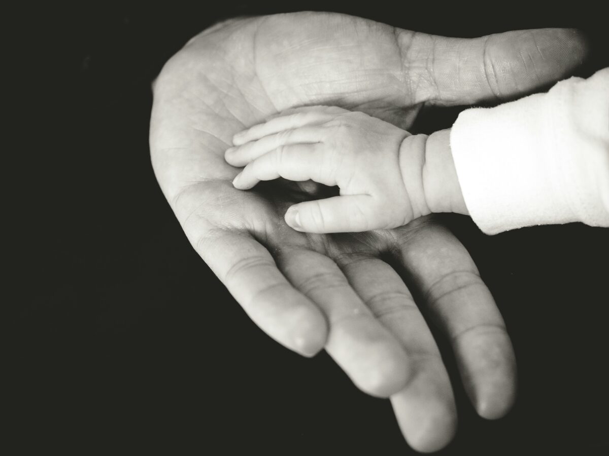 dalla parte dell'uomo (papà) mano di un neonato sopra la mano del papà in bianco e nero