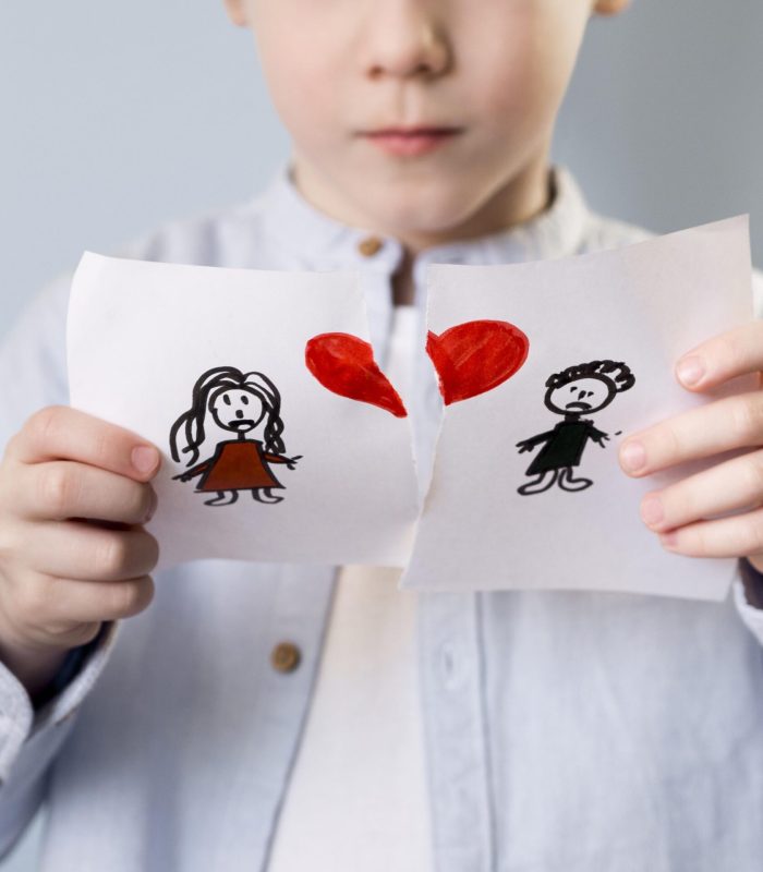 LA/IL TATA/O NELLA SEPARAZIONE: ANCORA O ARBITRO? bambino che spezza un disegno con mamma e papà e un cuore centrale