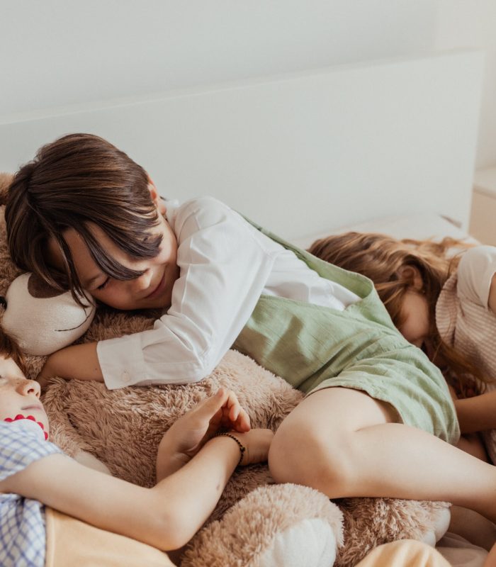 bambini dormono sul lettone abbracciati a un peluche